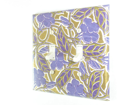 A large bluish purple floral design covers this double toggle swtich plate, with a metallic gold background weaving in and out of the tan leaves and vines.